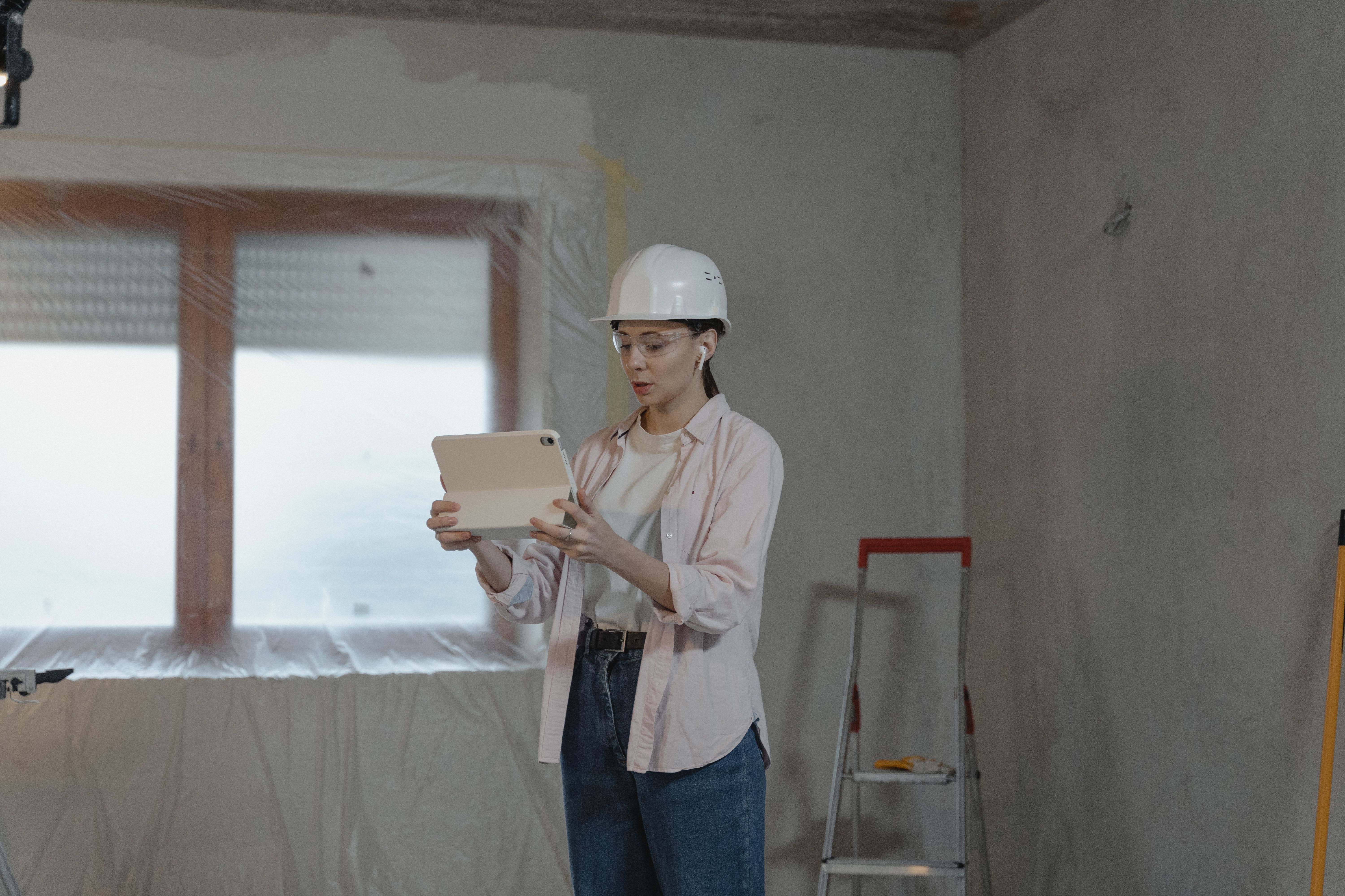 Construction professional using a tablet in an unfinished interior during a renovation project.