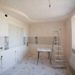 Spacious kitchen under renovation with ladder and tools, documenting a construction project in progress.