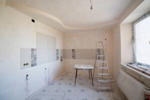 Spacious kitchen under renovation with ladder and tools, documenting a construction project in progress.