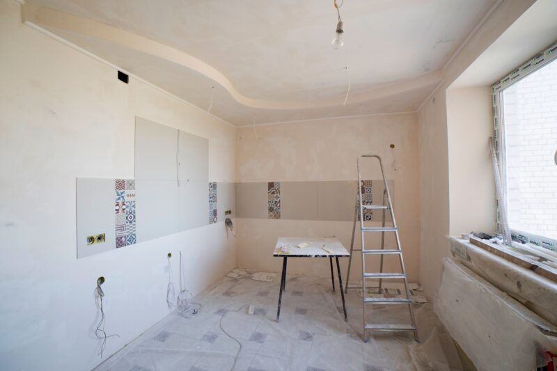 Spacious kitchen under renovation with ladder and tools, documenting a construction project in progress.
