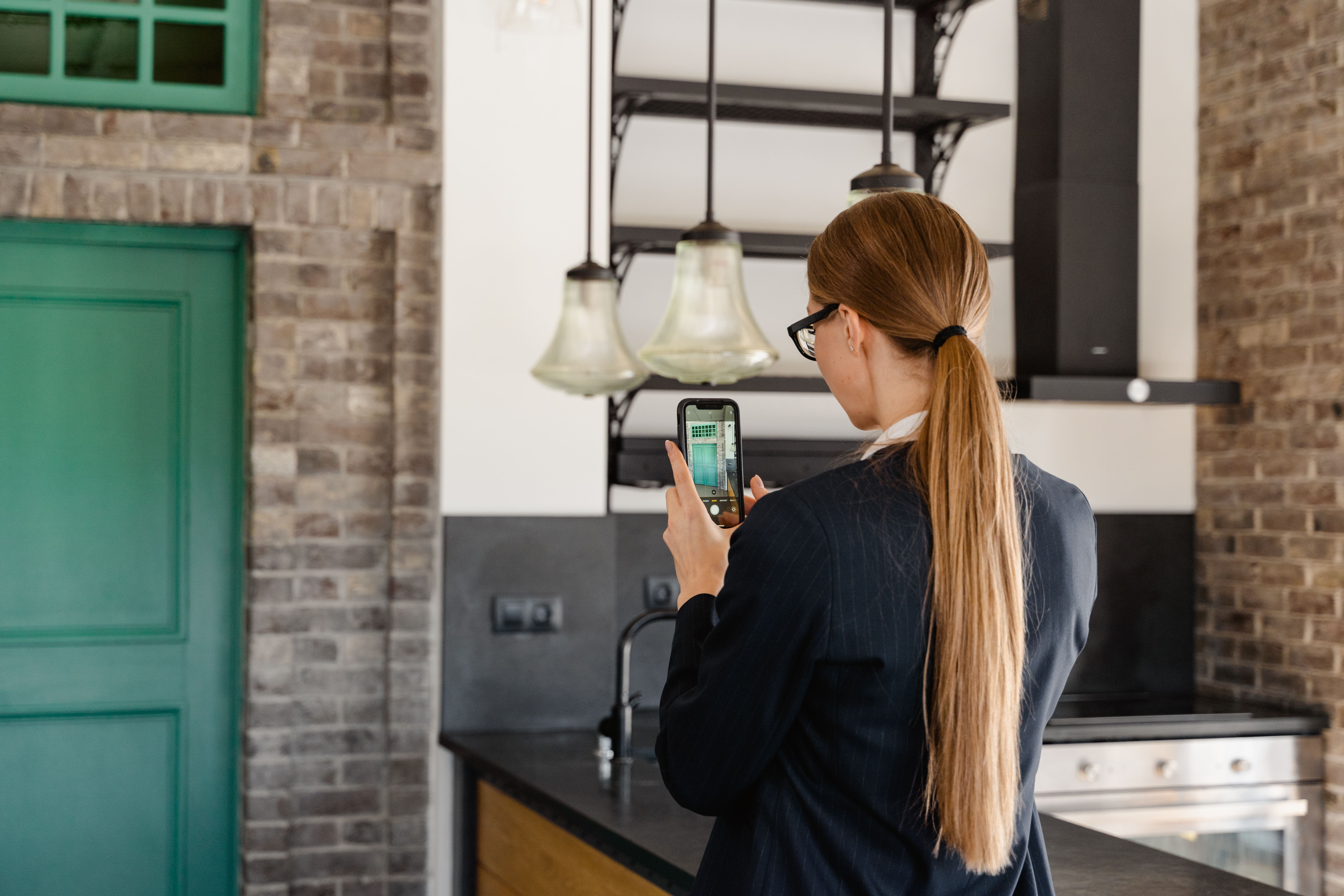 Person photographing a stylish kitchen renovation with a smartphone.